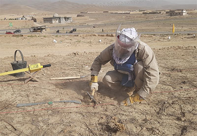 アフガニスタンの地雷原で除去活動をする作業員