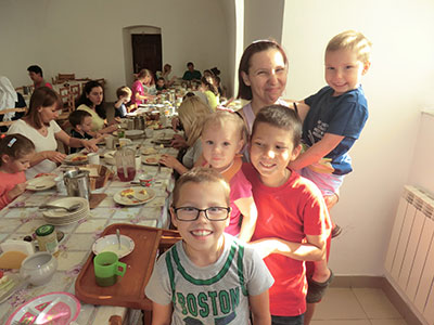 AARが支援する、ウクライナ国内避難民の母親と子どもたち。そばにテーブルがあり親子が食事をしている。みんな笑顔