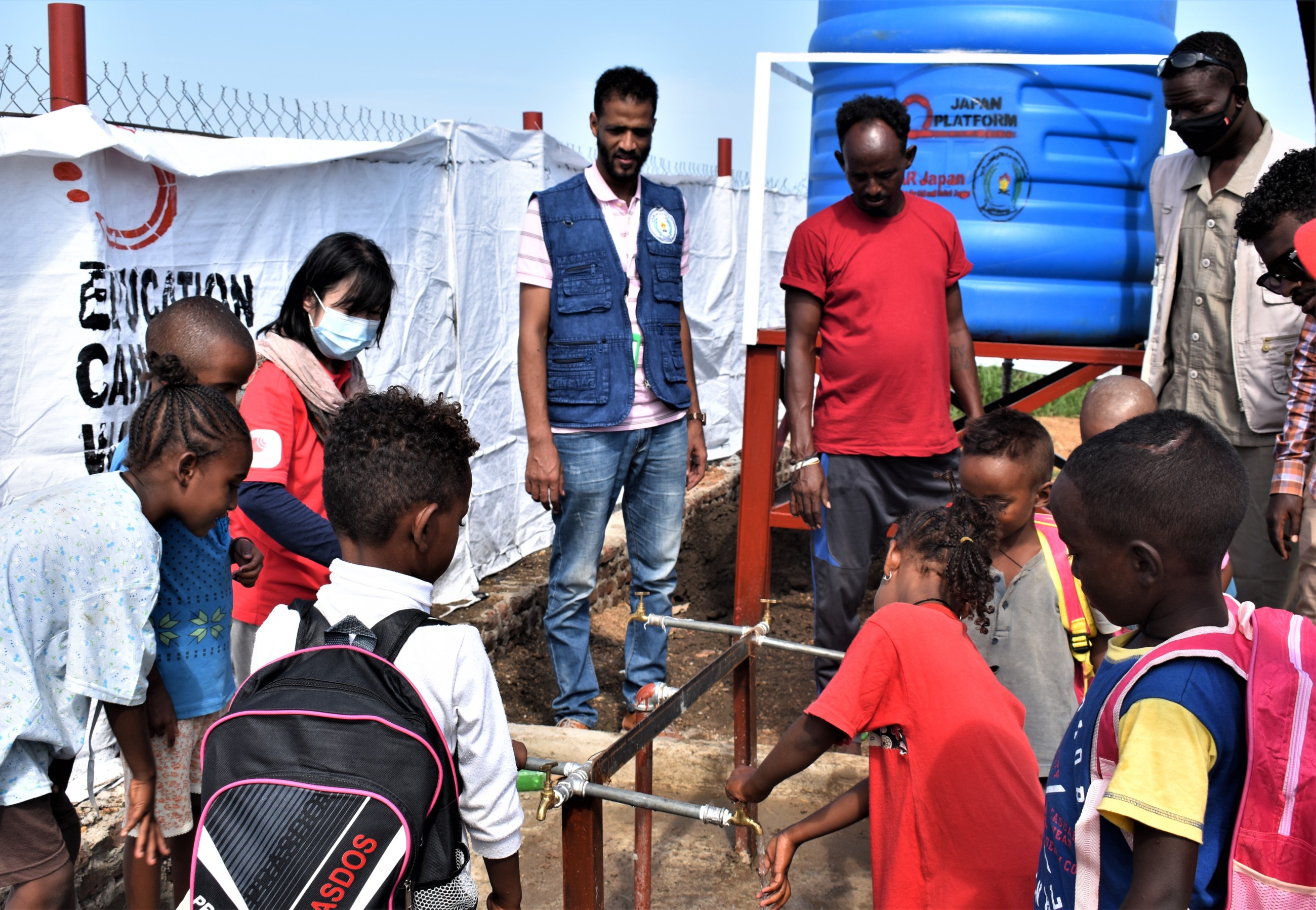 子どもたちや避難民10名近くが手洗い場に集まっている