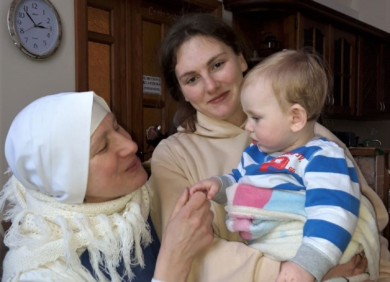 修道女会のシスター（左）お母さんの腕に抱かれた赤ちゃんをあやしている