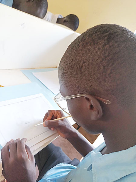絵を描くケニアの難民居住地の学生