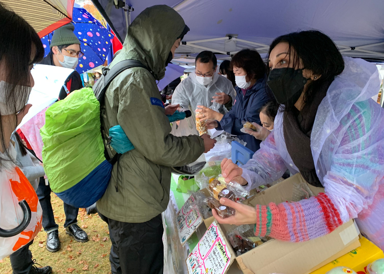 埼玉県川口市で開催された「難民・移民フェス」に、「さへる畑の」仲間と一緒に参加し、お菓子などを販売するサヘルさん（右）の写真