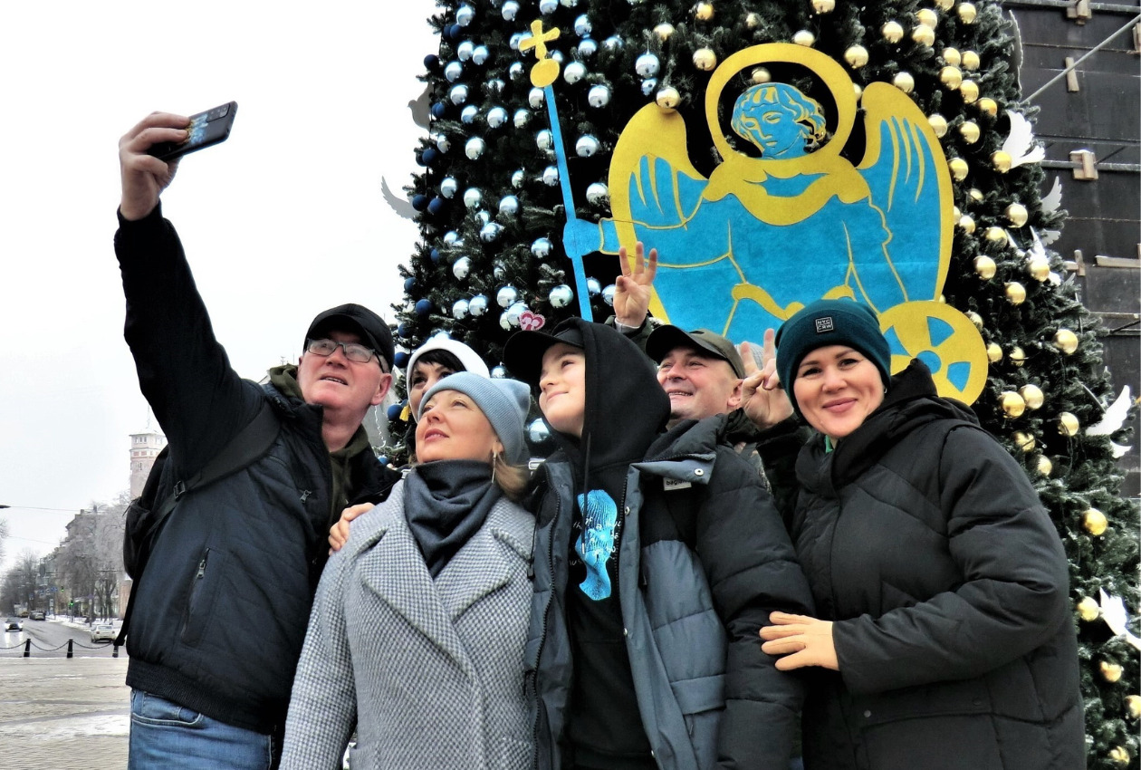 聖ソフィア大聖堂前の広場に飾られたクリスマスツリーを背景に、平和への願いを込めて記念撮影する家族。当地では1月20日頃まで クリスマスを祝う＝キーウで2023年1月15日（中坪央暁撮影）