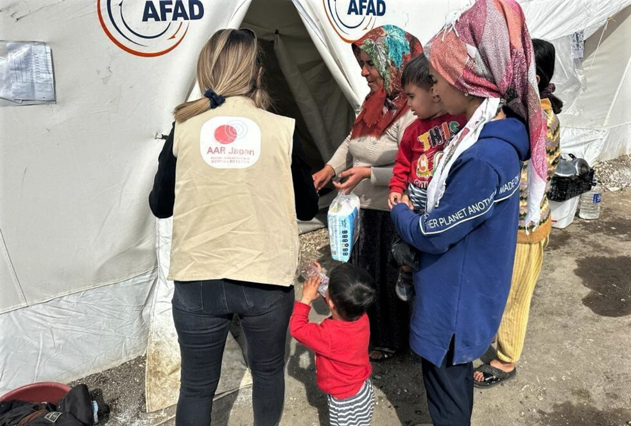 被災者のテントに支援物資を配付するAAR 職員の写真
