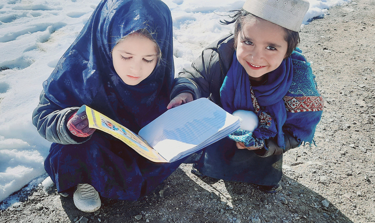 屋外で地雷回避教育教材を読む子どもの写真