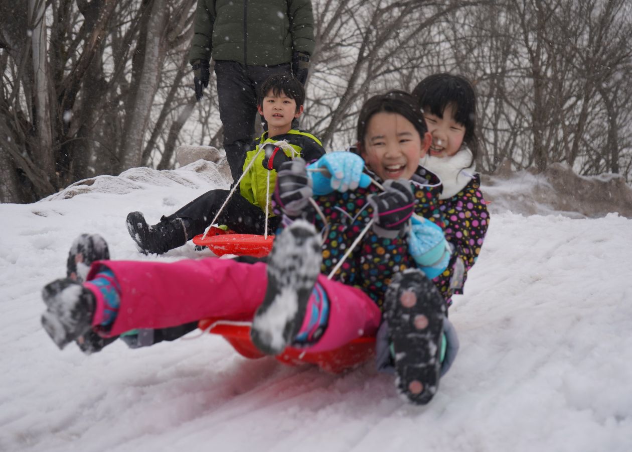 雪の中でそり遊びをする子どもたち