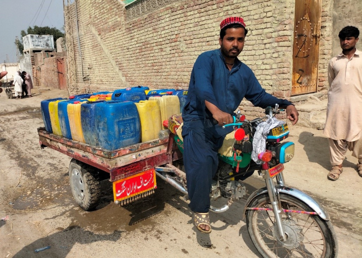 水のタンクを荷台に満載したバイクで水を売っている男性の写真