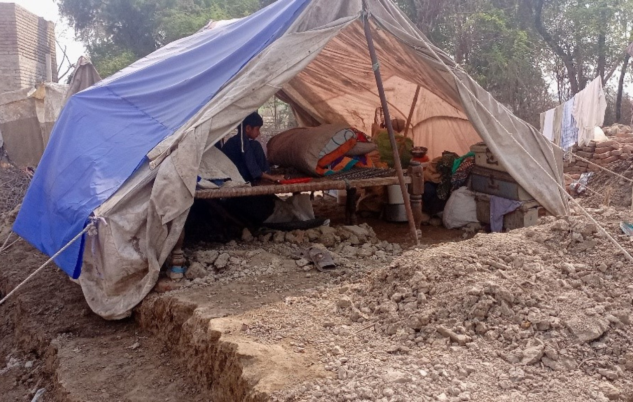 家が崩壊し粗末なテントで生活している被災者の写真