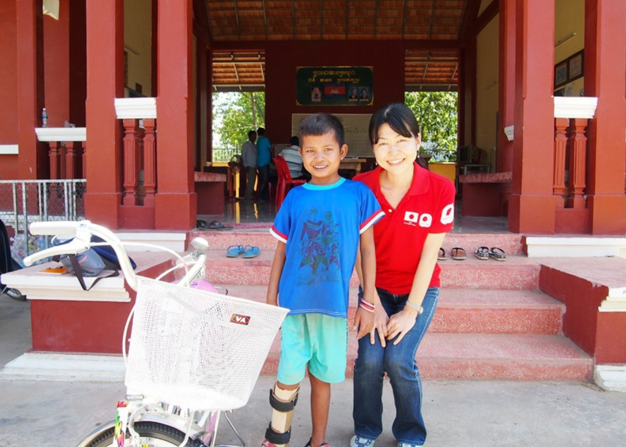 右足に障がいがある児童と園田の笑顔の写真　左側には自転車がある