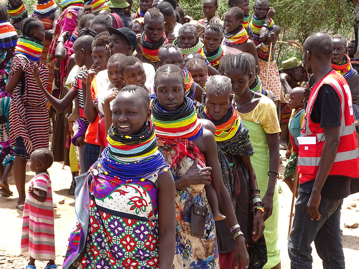 色鮮やかな衣装や首飾りをまとったケニアの人々が行列している