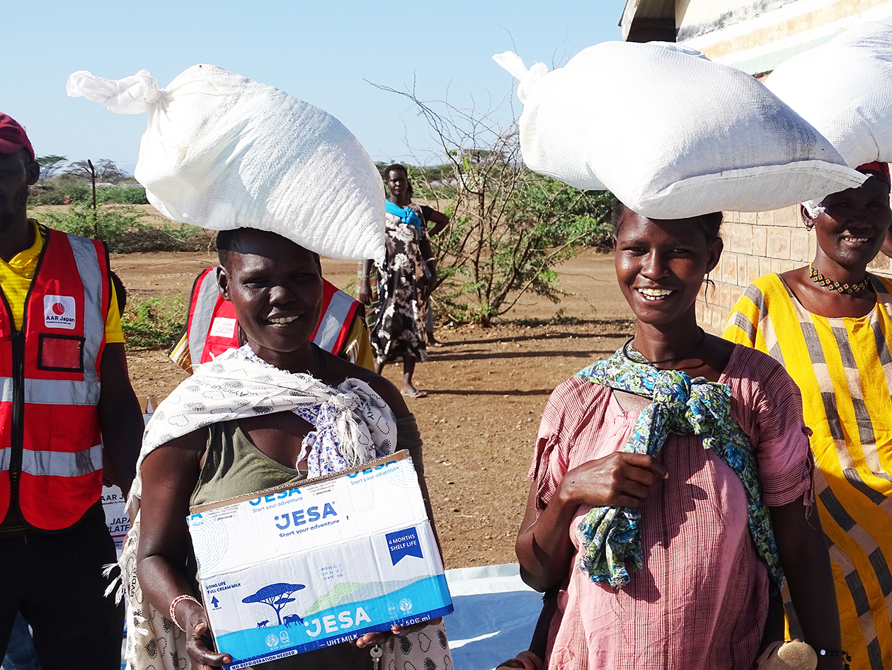 受け取った食料の袋を頭に乗せて運ぶケニアの人々