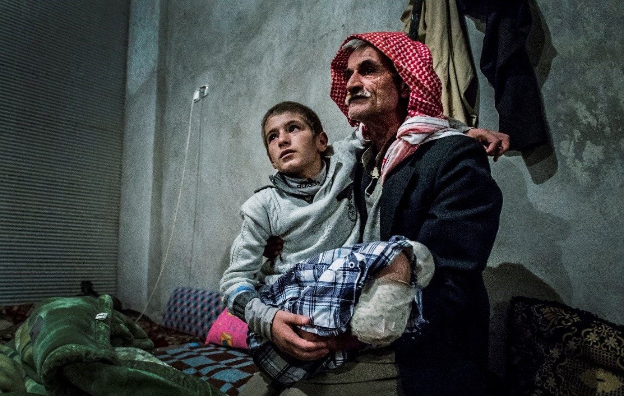 足を失ったシリア難民の男の子を抱く父親の写真