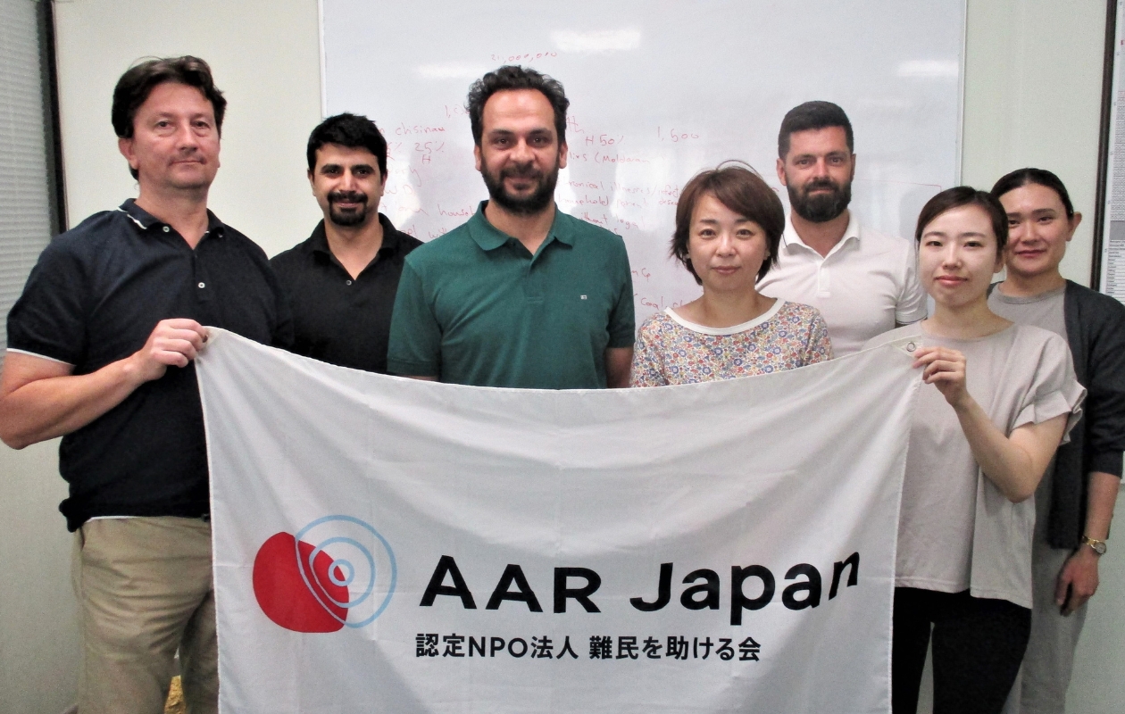 AARの旗を持ち、正面を向くAARキシナウ事務所職員と徳島新聞の木下記者