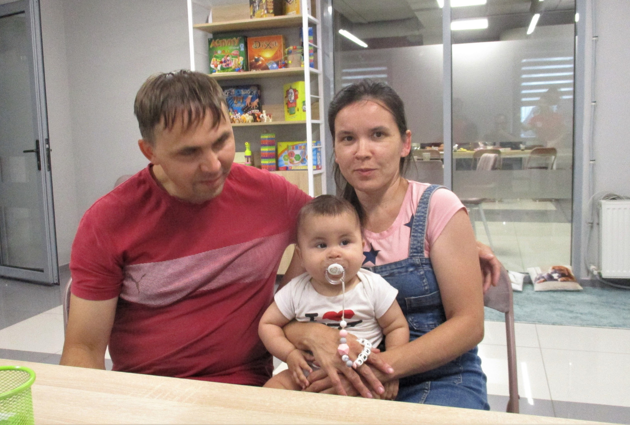 ウクライナ難民の母親が赤ちゃんを抱いている。横には父親がいる写真