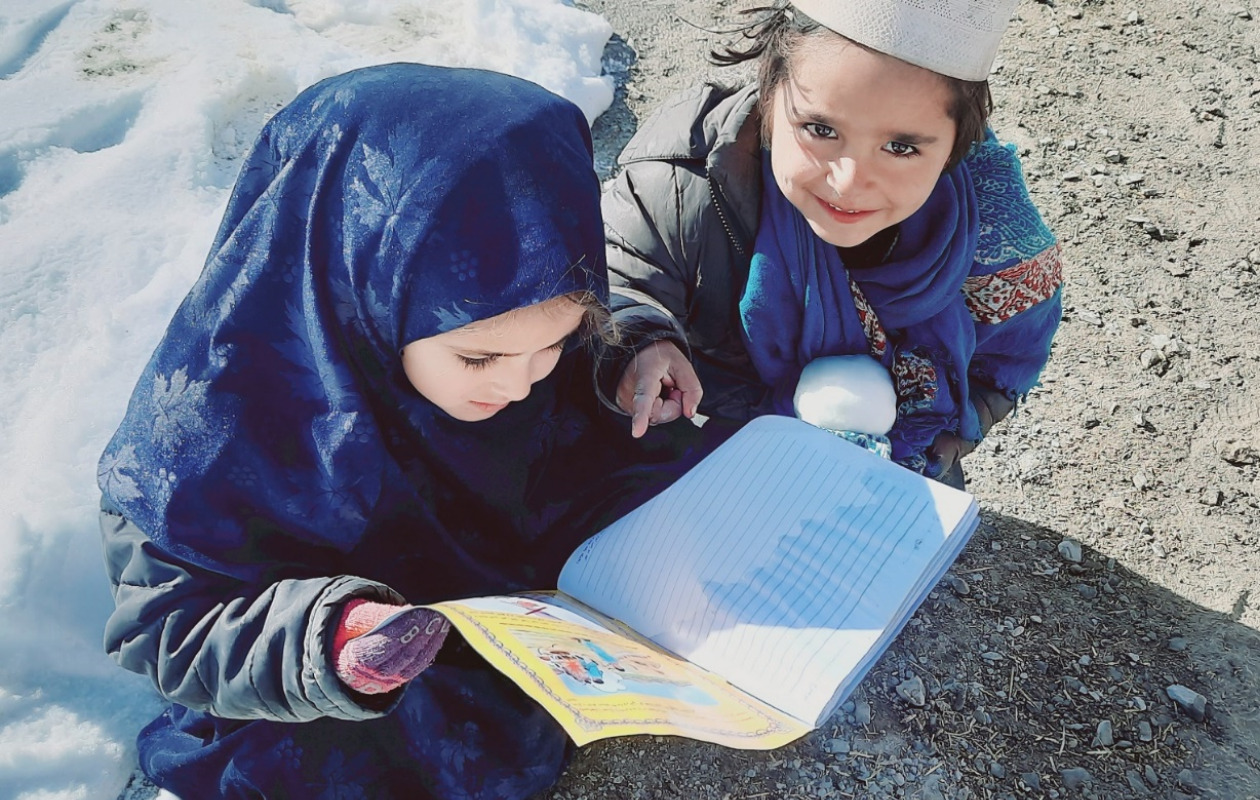 地雷回避教育教材を見ているアフガニスタン人の子ども2人の写真