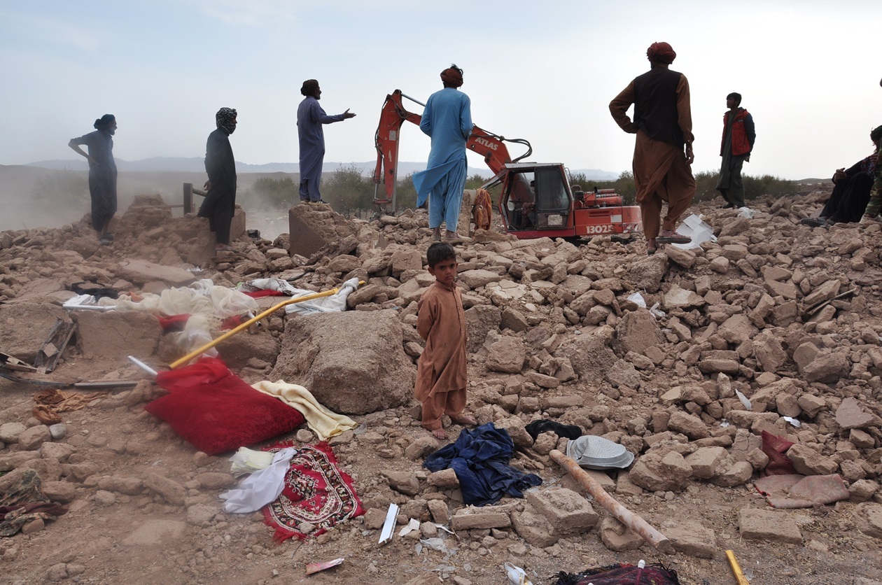 瓦礫の上で作業する住民6人。写真中央には子どもが立っている