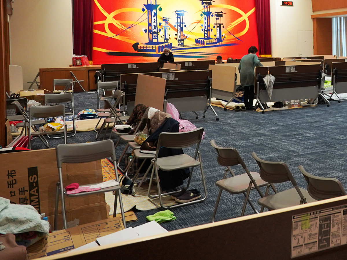 机や椅子を利用して被災者を受け入れている能都町役場2階のホールの写真