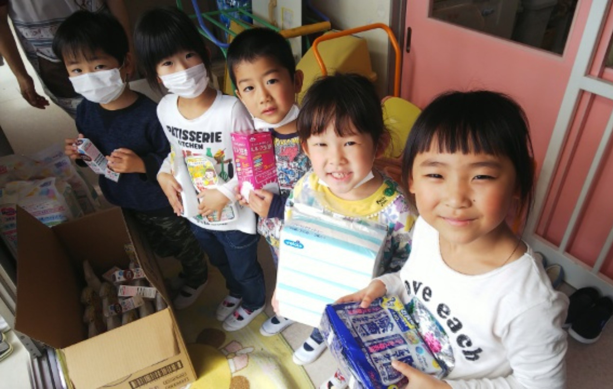 支援物資を手にして微笑む児童たち
