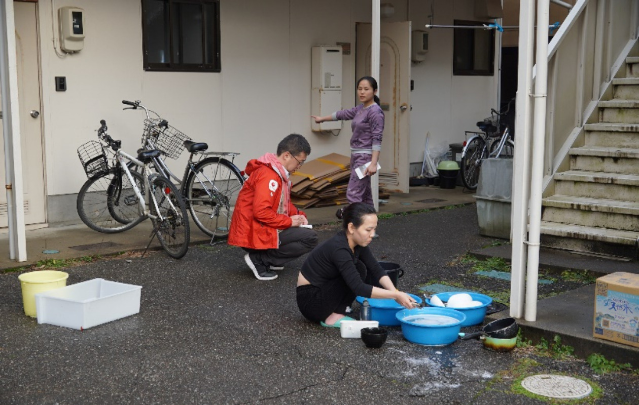 断水のためアパートの前で食器を洗うベトナム出身の女性