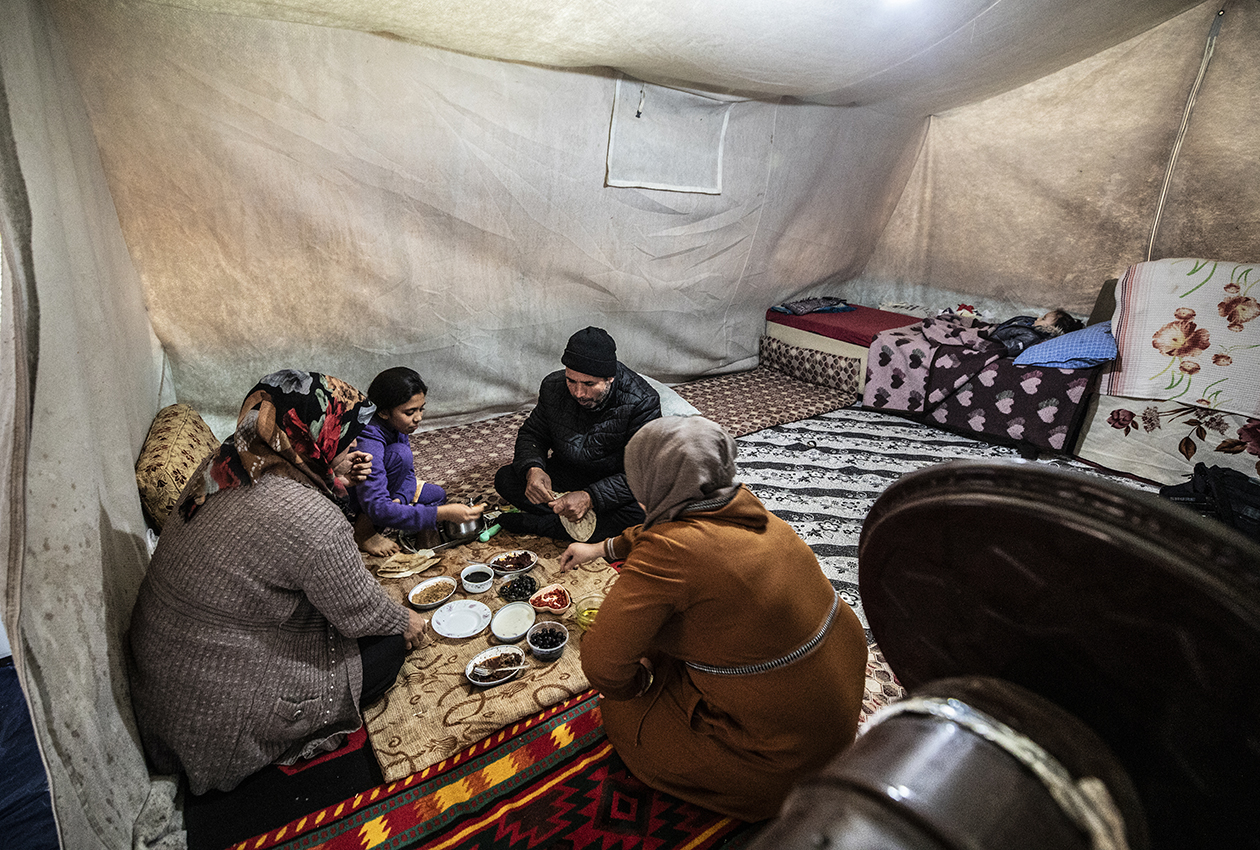 絨毯の敷かれたテントの中で食事をする家族