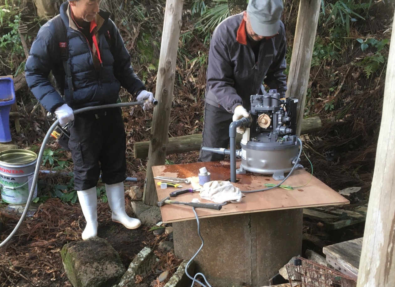 井戸に電動ポンプを設置する男性2名の写真