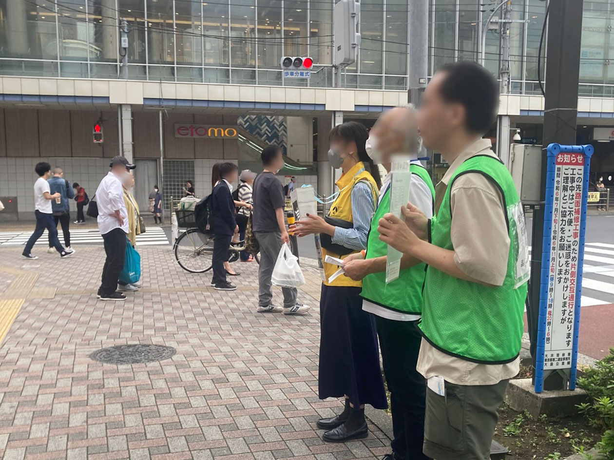 駅前の通りにボランティアが数名募金箱やチラシを手に持っている