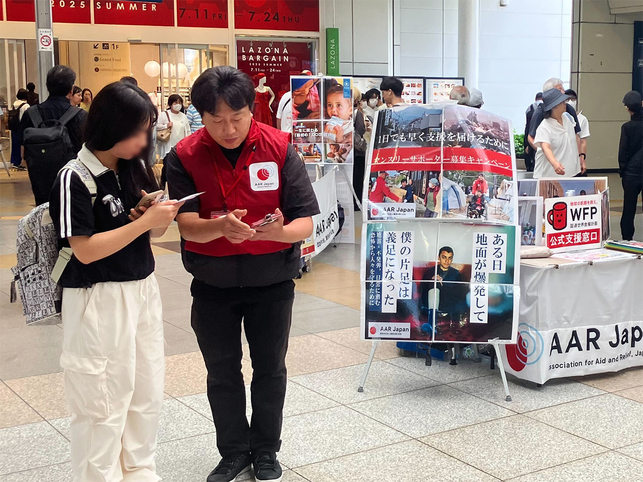 AARのベストを着た男性が女性に説明している