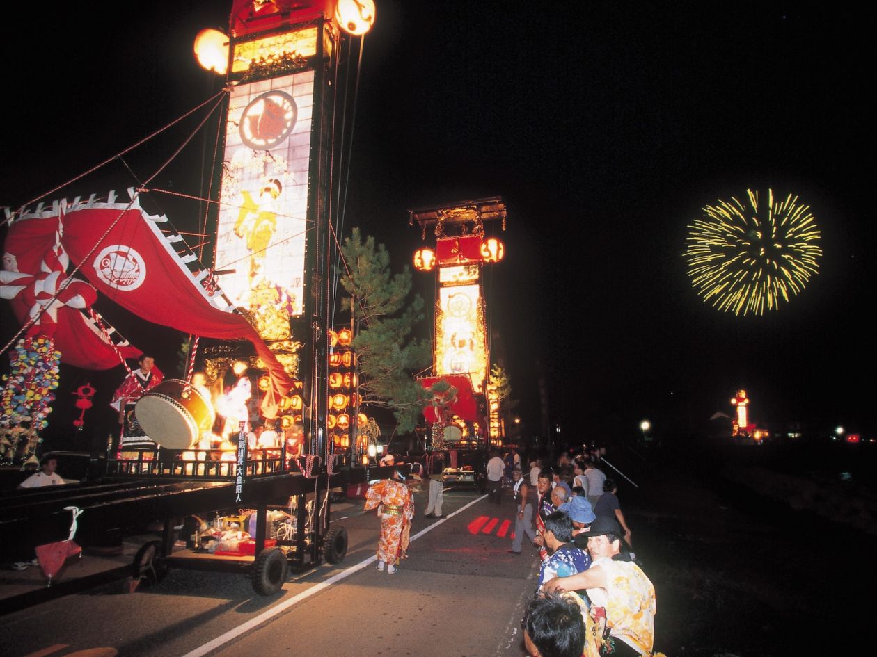 夏の夜道を、高さ4～5メートルの燈籠を載せた台車が動いている