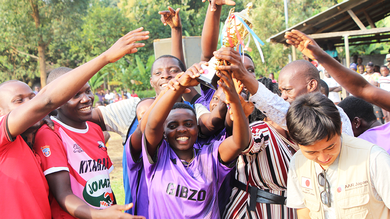 子どもたちが笑顔でトロフィーを上にあげている