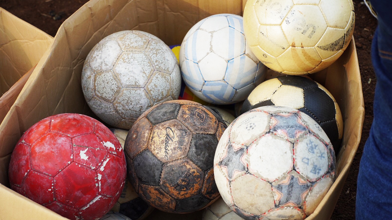使用感のあるサッカーボールがいくつか段ボール箱に入っている