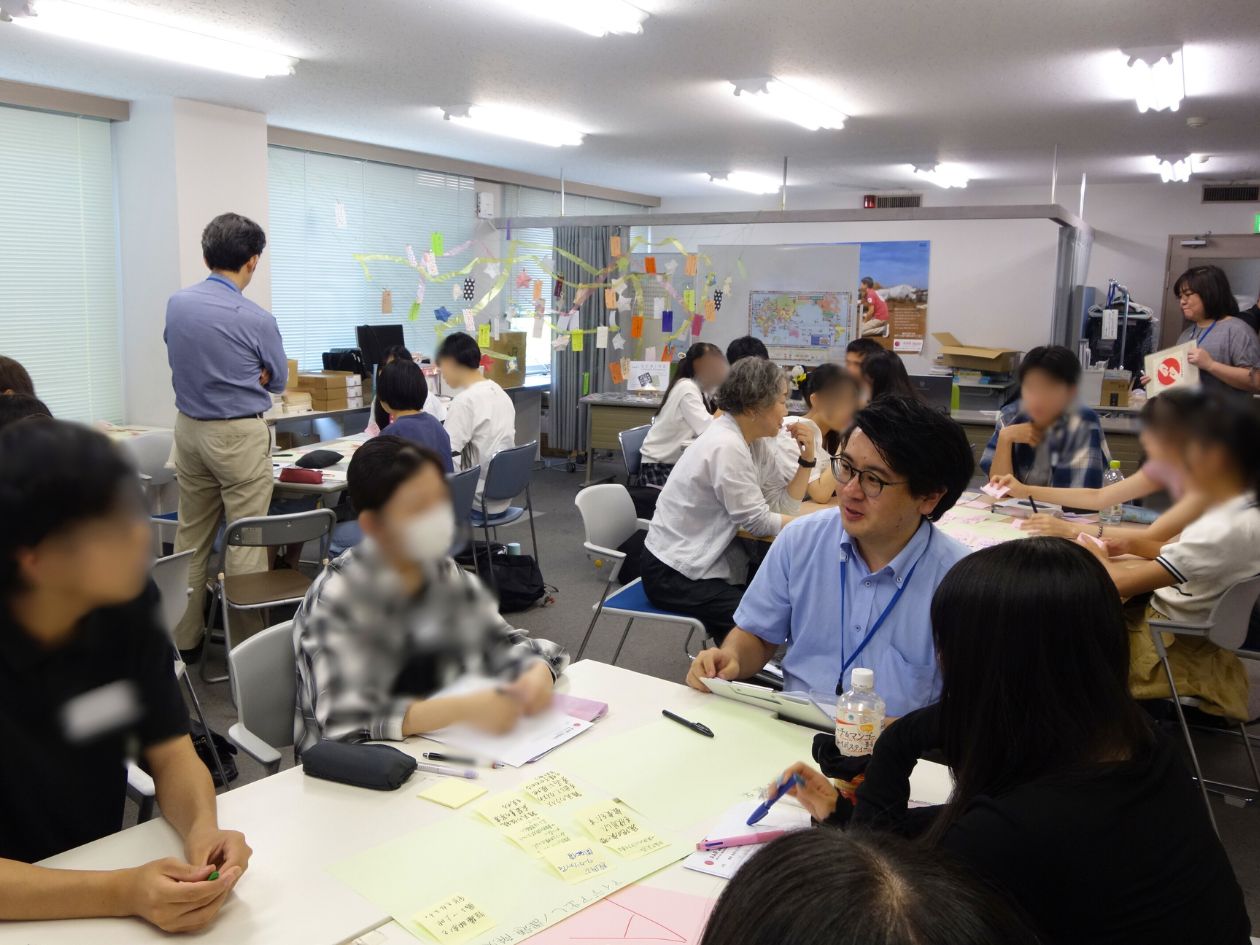 小会議室で5～6人のグループに分かれた高校生が話し合っている