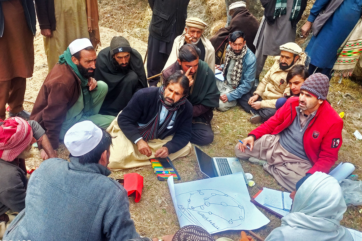 地面に座って村人と話し合うAAR職員