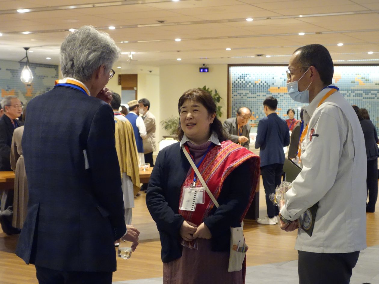 民族衣装を身に着けた女性が二人の男性と話している