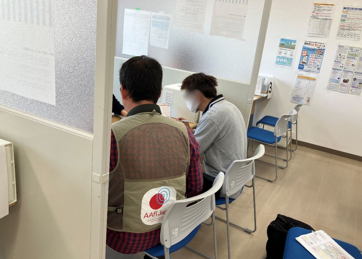 役所のブースに並んで座る男性２人