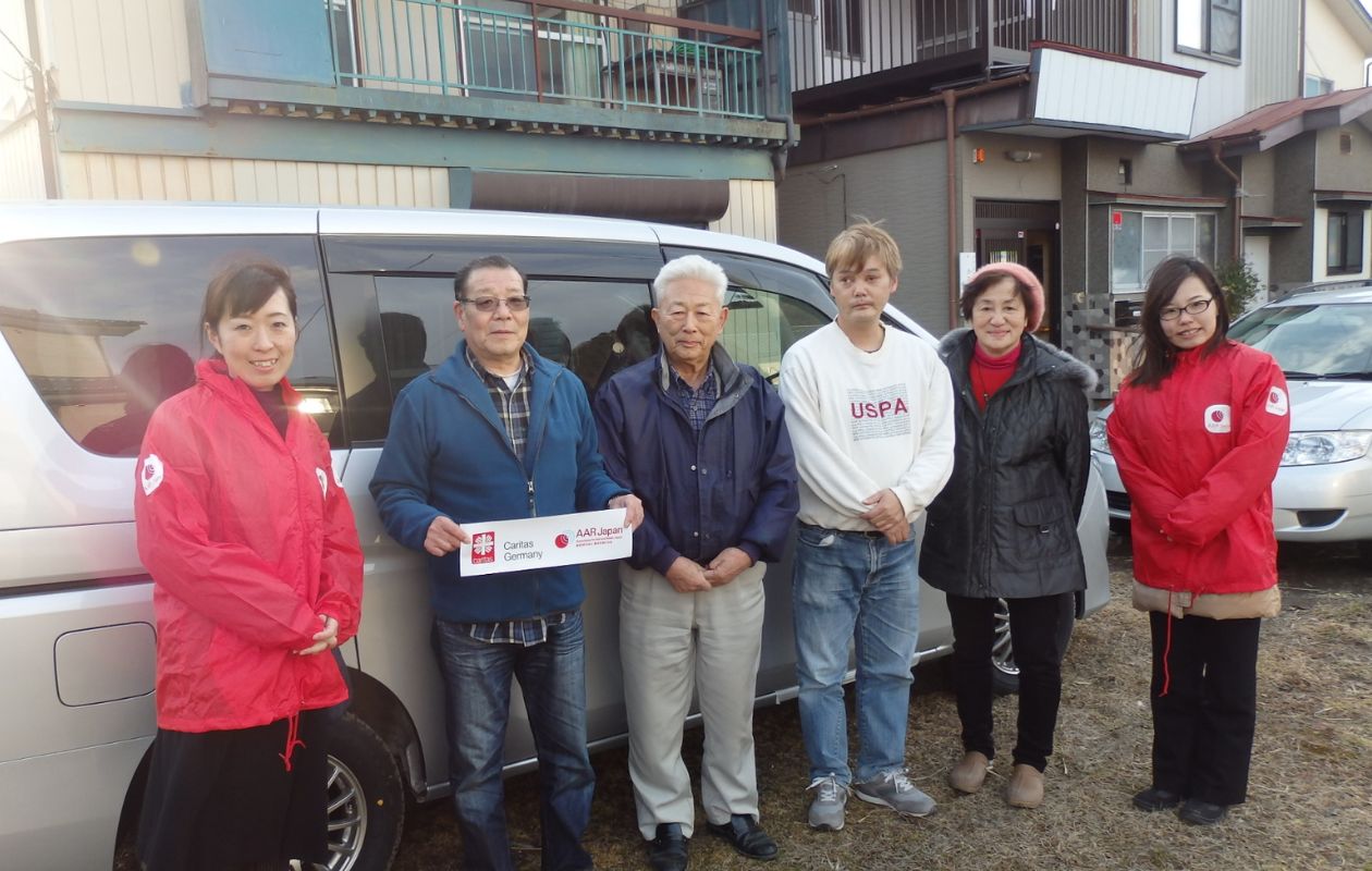 AARが寄贈した車の前に立つ、施設職員とAARスタッフ