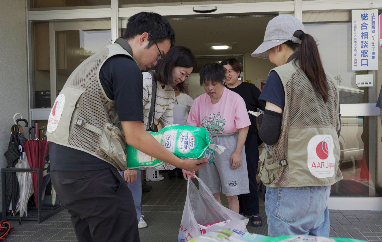 男性が入居者の女性に衛生用品を手渡している