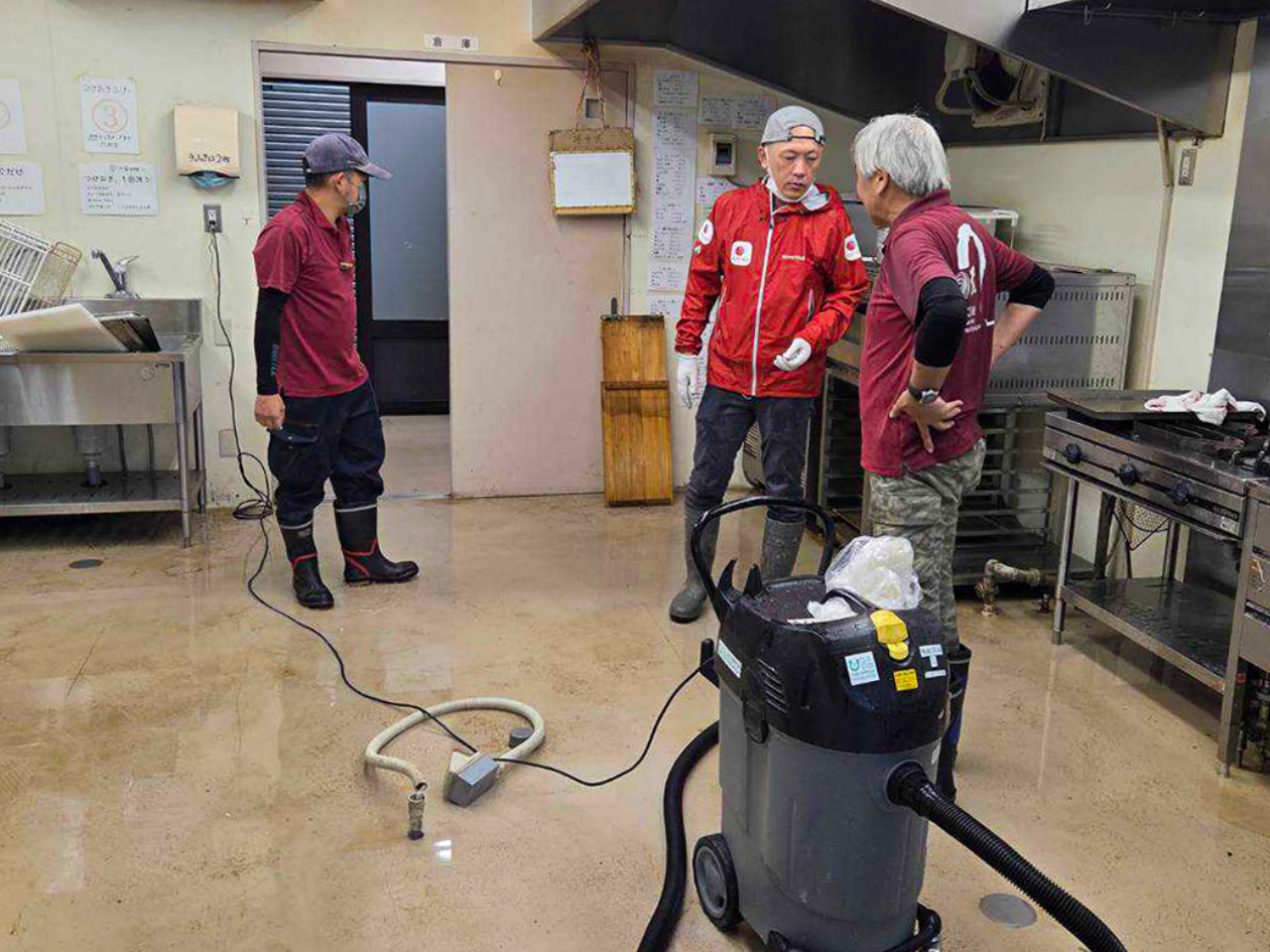 男性たちが浸水した室内の清掃をしている